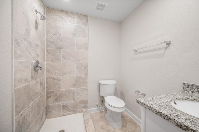 full bath with visible vents, toilet, a tile shower, vanity, and baseboards