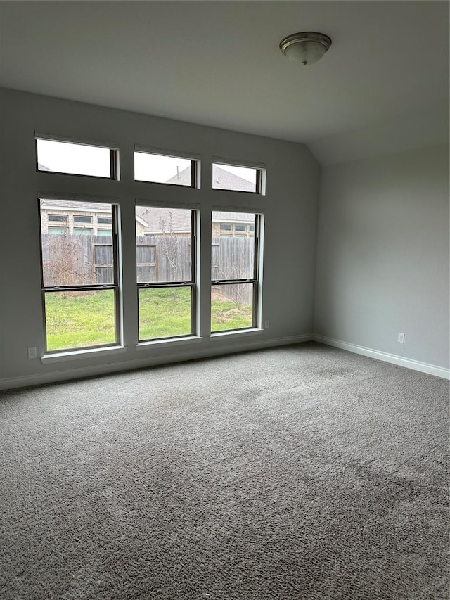 carpeted spare room with lofted ceiling and baseboards