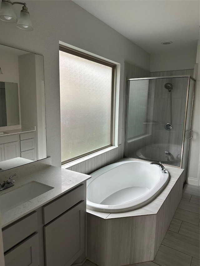 full bathroom with a stall shower, a bath, and vanity