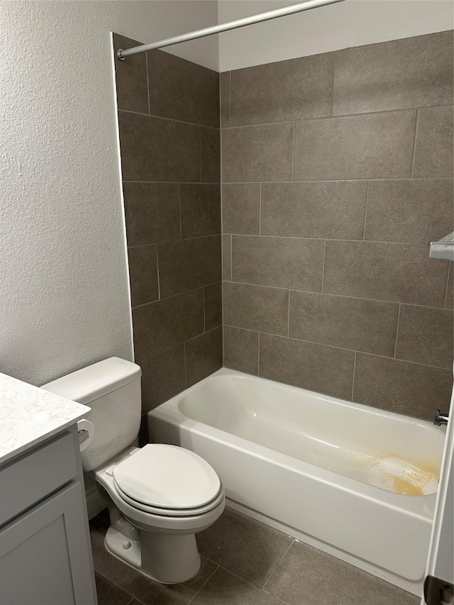 bathroom with a textured wall, toilet, washtub / shower combination, vanity, and tile patterned floors