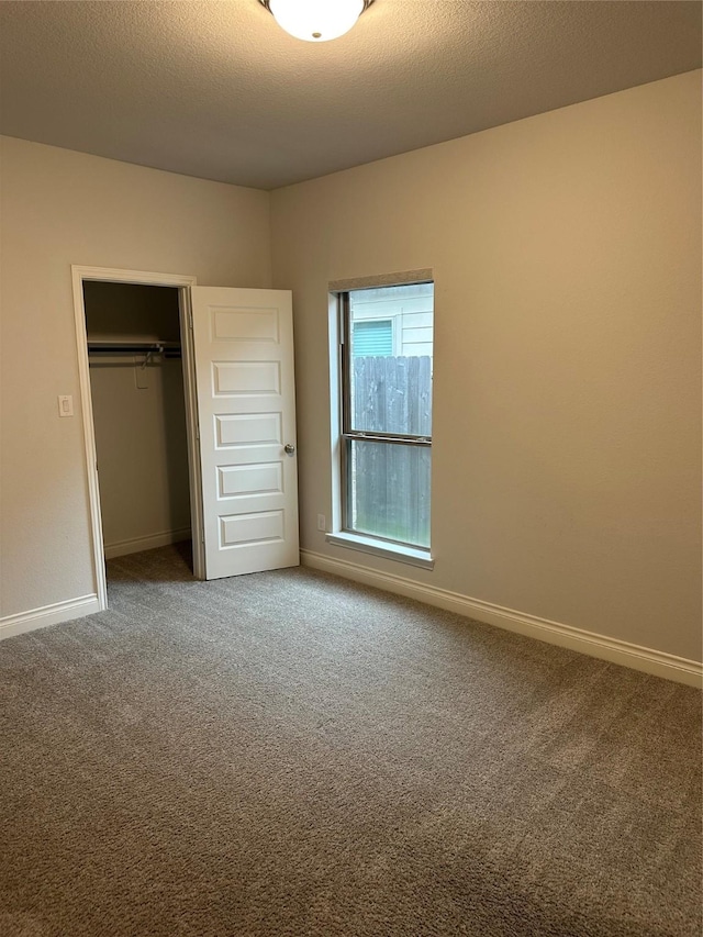 unfurnished bedroom featuring carpet floors, a closet, a textured ceiling, and baseboards