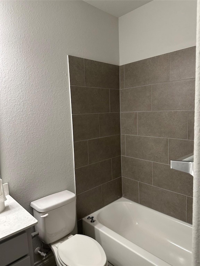 bathroom with a textured wall, shower / bath combination, vanity, and toilet