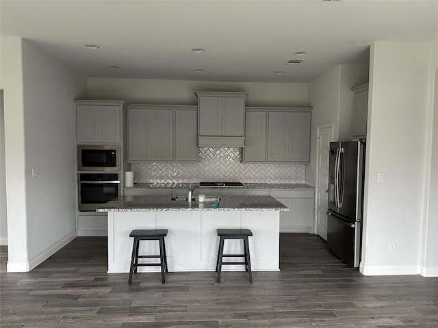 kitchen featuring custom exhaust hood, stainless steel appliances, decorative backsplash, and dark stone counters