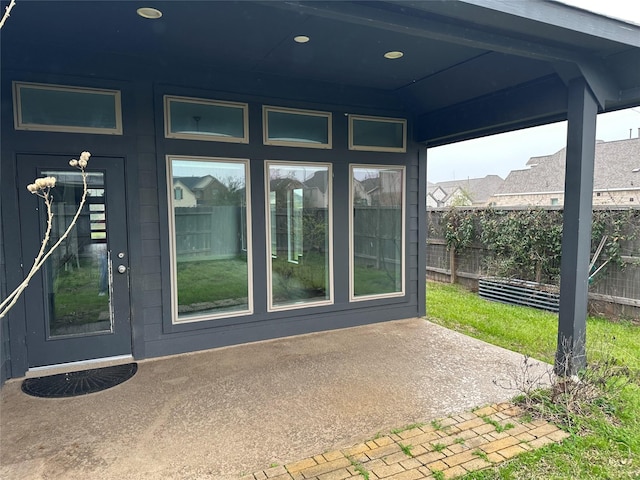 view of exterior entry featuring a patio area and fence