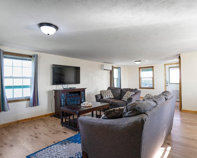 1821 County Road 201, Sargent, TX 77414 - living area with a wall mounted AC, light wood-style flooring, a textured ceiling, and a fireplace