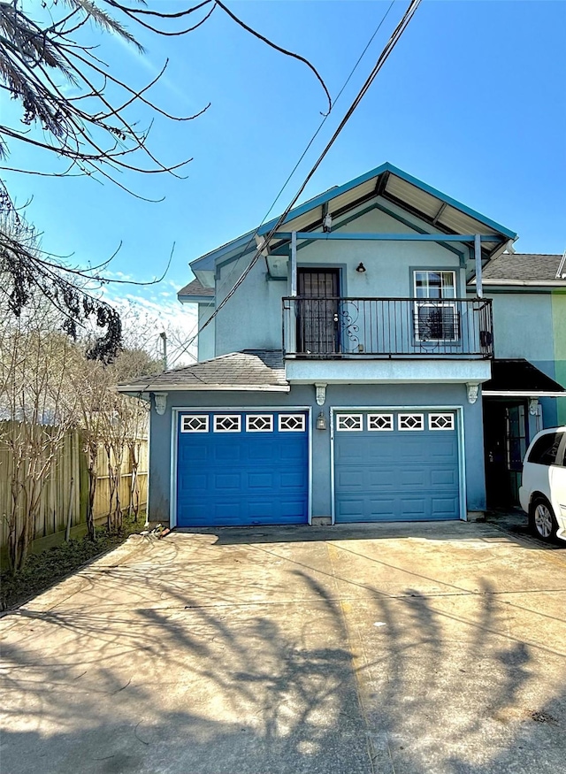 view of front of home featuring a garage, concrete driveway, a balcony, and stucco siding