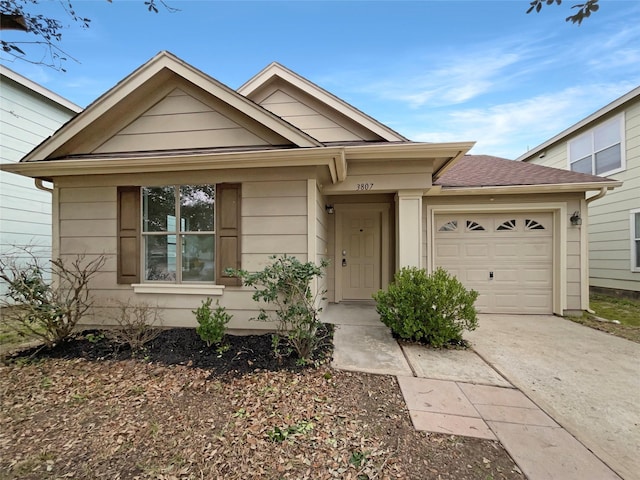 view of front of property featuring concrete driveway, a shingled roof, and an attached garage