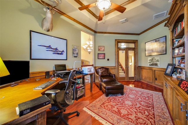 office area with a wainscoted wall, wood finished floors, visible vents, a ceiling fan, and ornamental molding