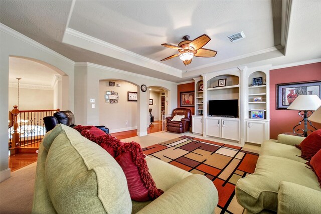 living area featuring arched walkways, a raised ceiling, visible vents, and crown molding