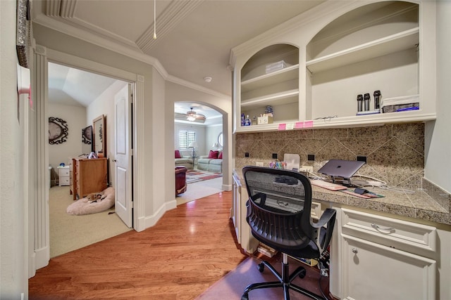 office with arched walkways, light wood-style floors, ornamental molding, ceiling fan, and baseboards