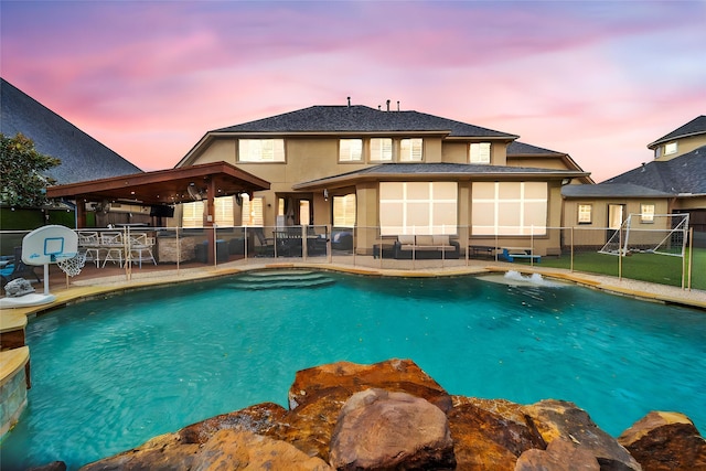 pool at dusk with a patio area, fence, and a fenced in pool