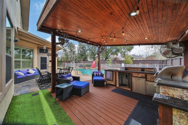 wooden terrace with an outdoor kitchen, a fenced backyard, a sink, an outdoor living space, and a fenced in pool