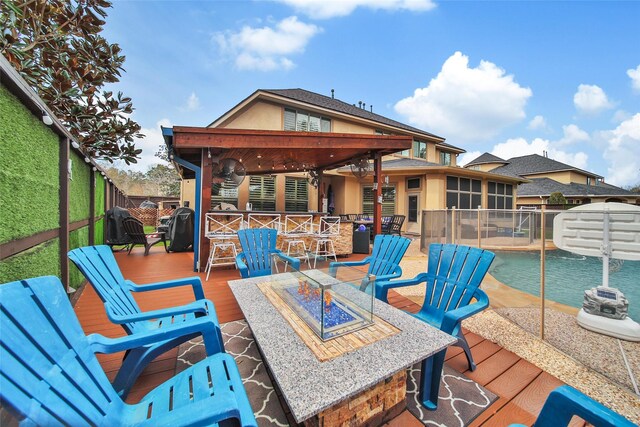 wooden deck with a fire pit, a sunroom, a fenced backyard, and a pool