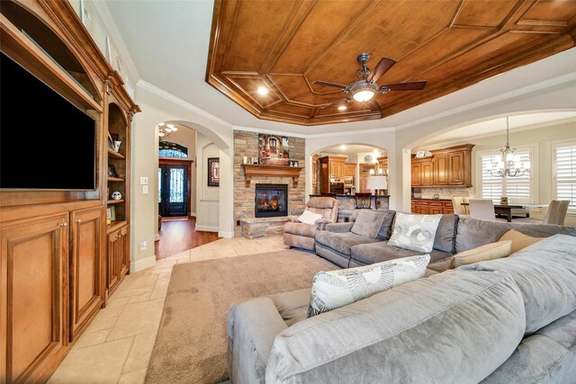 living area featuring arched walkways, a raised ceiling, wood ceiling, crown molding, and a fireplace