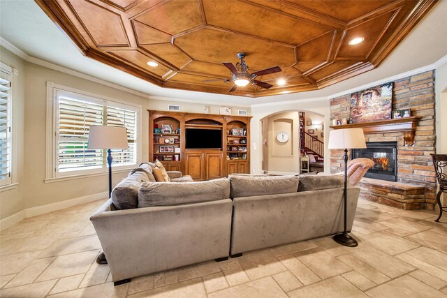 living area with arched walkways, a fireplace, crown molding, ceiling fan, and baseboards