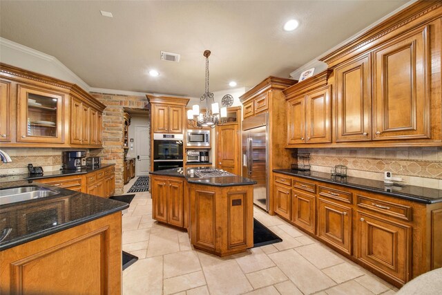 kitchen featuring built in appliances, brown cabinetry, a sink, and visible vents