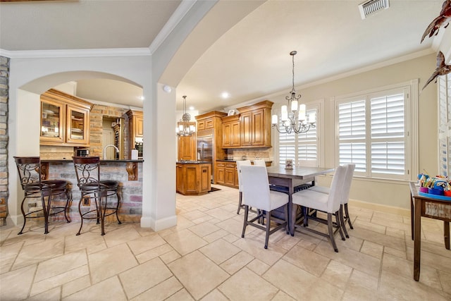 dining space with baseboards, ornamental molding, visible vents, and an inviting chandelier