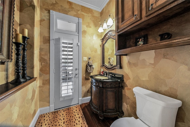 bathroom with toilet, ornamental molding, vanity, wood finished floors, and baseboards