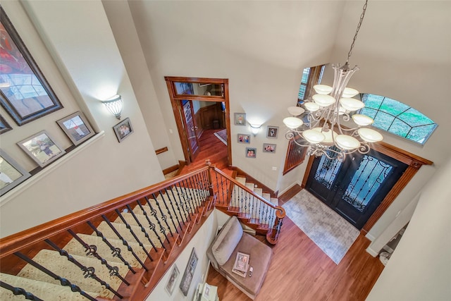 foyer entrance featuring a chandelier, a high ceiling, wood finished floors, baseboards, and stairway