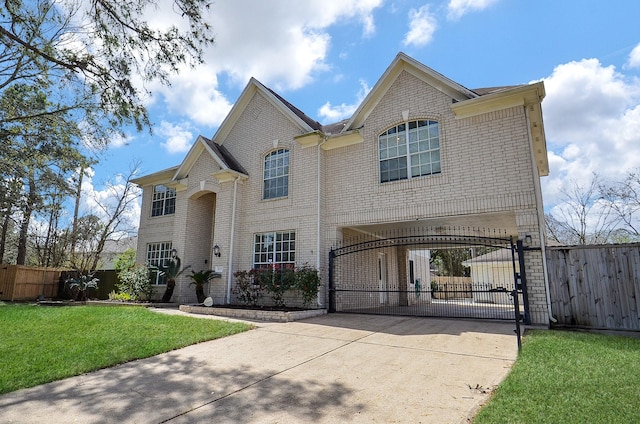 view of front facade featuring driveway, a gate, fence, a front yard, and brick siding