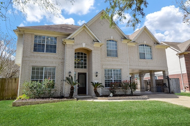 traditional-style house with concrete driveway, fence, a front yard, a carport, and brick siding