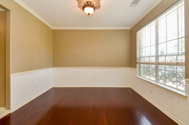 empty room featuring dark wood-style floors, visible vents, ornamental molding, and baseboards