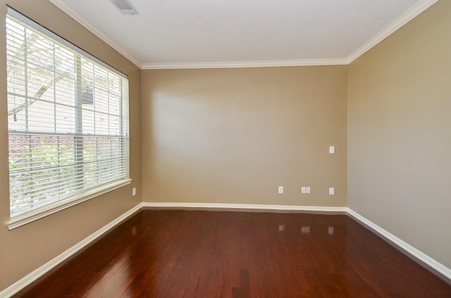 empty room featuring dark wood-style floors, visible vents, baseboards, and ornamental molding