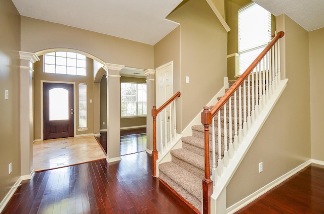 entrance foyer with baseboards, ornate columns, and hardwood / wood-style flooring