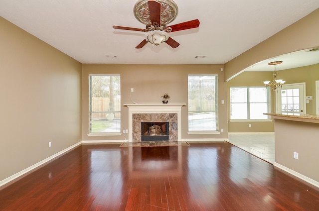 unfurnished living room with baseboards, visible vents, wood finished floors, and a high end fireplace