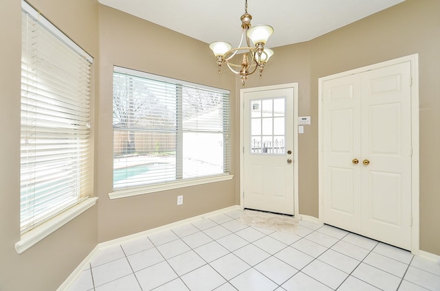 foyer entrance with baseboards, light tile patterned flooring, and an inviting chandelier