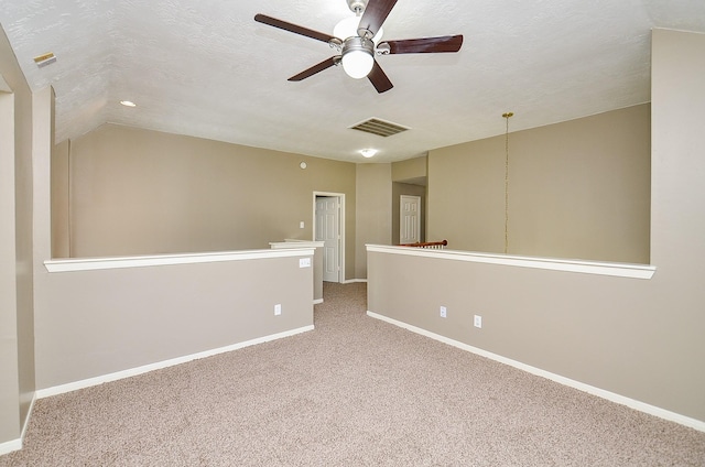 carpeted empty room featuring visible vents, a textured ceiling, and baseboards