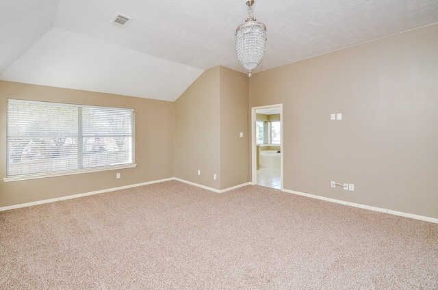 carpeted spare room with lofted ceiling, a textured ceiling, visible vents, baseboards, and an inviting chandelier