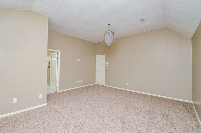 carpeted spare room featuring lofted ceiling, a textured ceiling, and baseboards