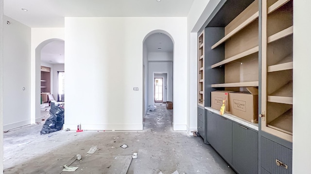 corridor featuring baseboards and arched walkways