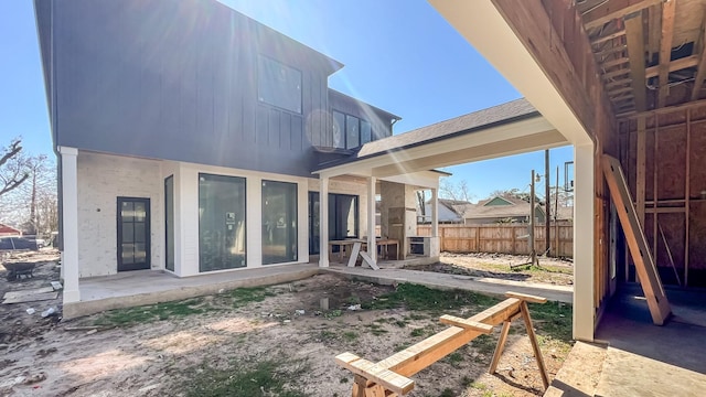 rear view of property with roof with shingles, fence, and a patio