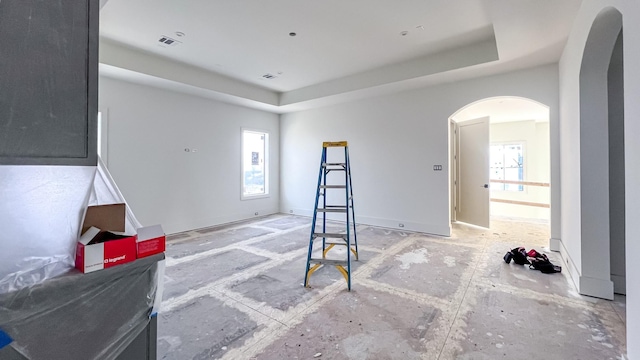 interior space featuring arched walkways, a tray ceiling, visible vents, and a healthy amount of sunlight