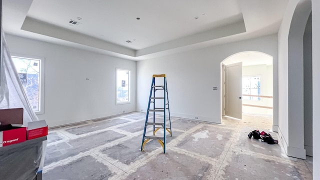 interior space featuring visible vents, a tray ceiling, and arched walkways