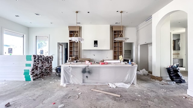 kitchen with arched walkways, decorative light fixtures, open shelves, visible vents, and white cabinets