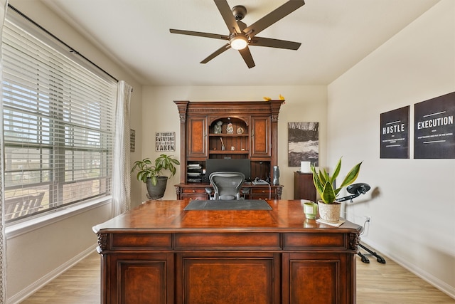 office space with light wood-type flooring, ceiling fan, and baseboards