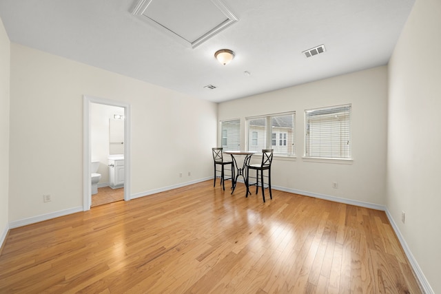 interior space featuring attic access, baseboards, visible vents, and light wood finished floors