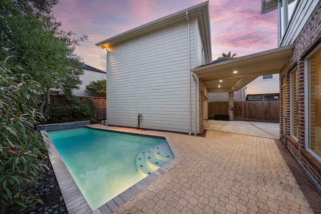 pool at dusk featuring a patio area, a fenced in pool, and a fenced backyard