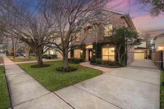 view of front of property featuring brick siding, a lawn, and a gate