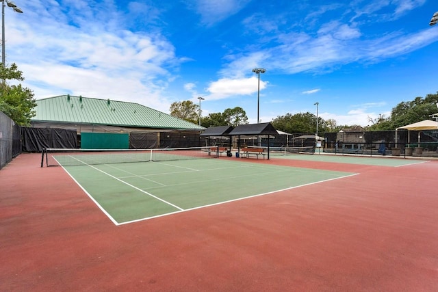 view of tennis court with community basketball court and fence