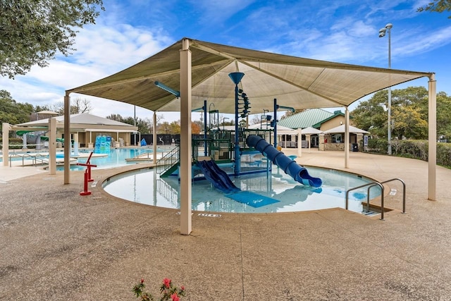 community pool featuring playground community, a water slide, and a patio area