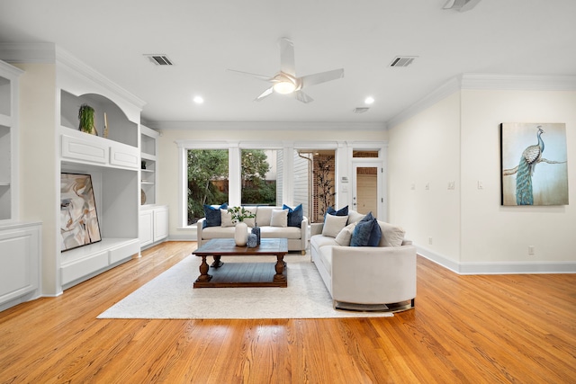 living area featuring visible vents, baseboards, crown molding, and light wood-style floors