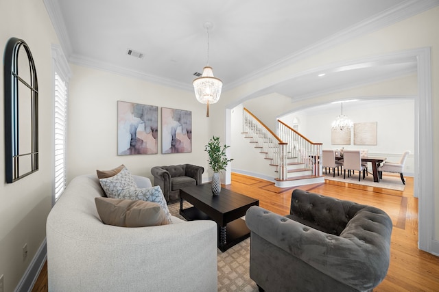 living room featuring arched walkways, ornamental molding, stairs, and wood finished floors