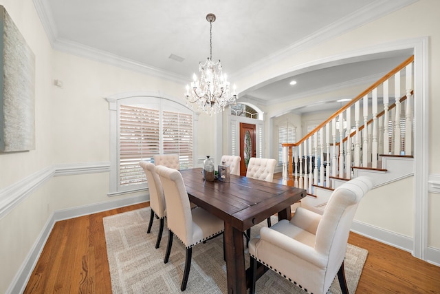 dining area with ornamental molding, wood finished floors, baseboards, and a chandelier