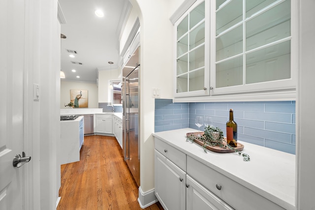 kitchen with glass insert cabinets, backsplash, visible vents, and white cabinets