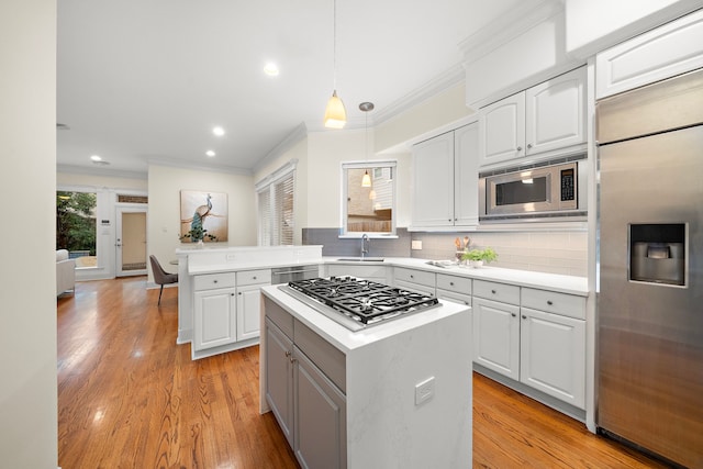 kitchen with light wood finished floors, built in appliances, light countertops, decorative backsplash, and a sink