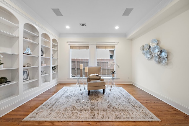 sitting room with visible vents, crown molding, baseboards, and wood finished floors